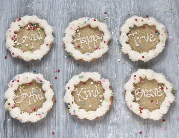6 round sugar cookies with words Loyal, Happy, True, Kind, Joyful, and Brave